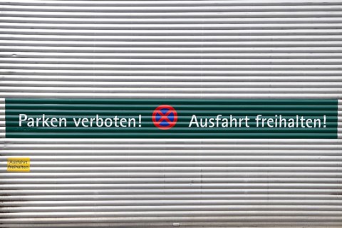 Rolltor mit der Aufschrift "Parken verboten und Ausfahrt freihalten" auf Deutsch