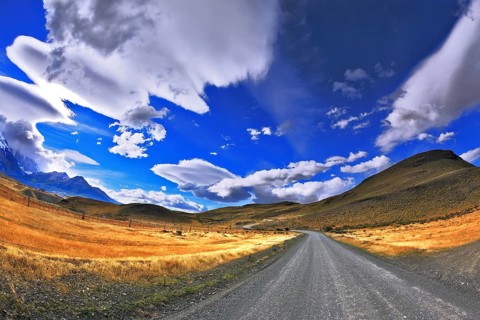 Patagonia. A dirt road in the Chile National Park Torres del Paine. Magic clouds incredible shapes