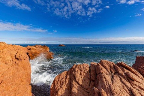 Coastal landscape with red rocks and surf in blue sky and sunshine, Spiaggia di Cala E'Luas,