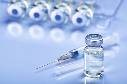 Single use syringe for injection treatment on medical table with vials of liquid drug doses flu