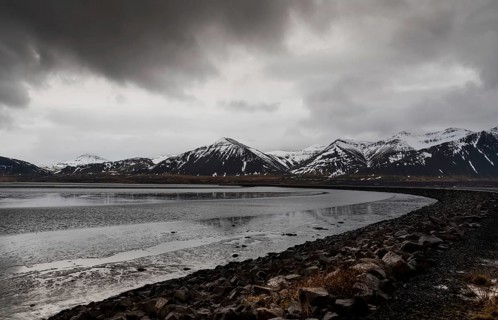Icelandic dramatic landscape with frozen lake and mountains covered in snow in Iceland