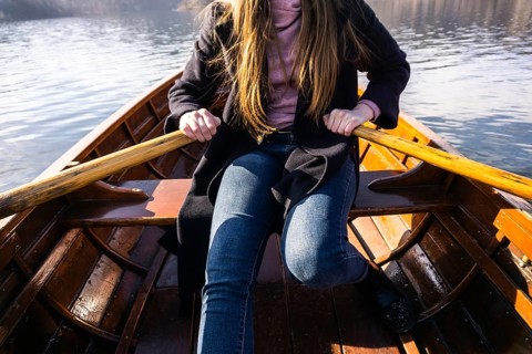 Young woman using paddle on a wooden boat, Lake Bled Slovenia rowing on wooden boats on a sunny day