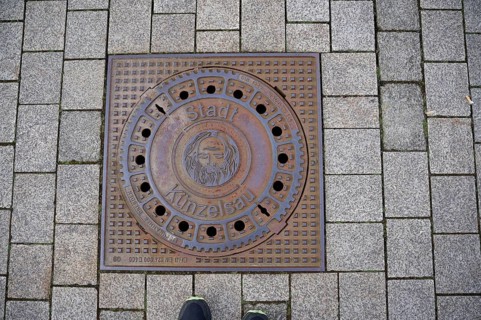 Manhole cover with motif on John the Baptist, Bible, town coat of arms, coat of arms, Künzelsau,