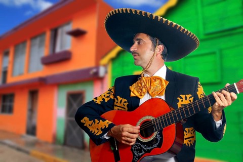 Charro Mariachi singer playing guitar in Mexico houses background