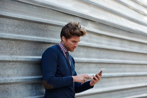 Young businessman texting smartphone phone on the street metal fence
