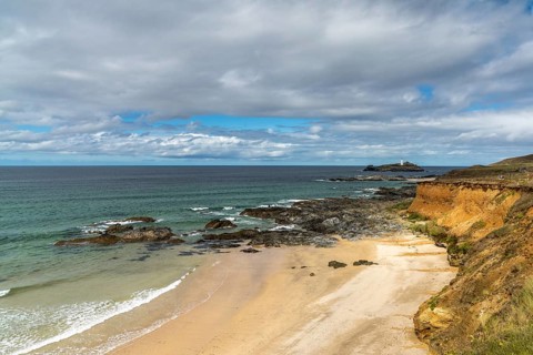 View of St. Ives Bay in Cornwall and small beach near Gwithian with the Godrevy Lighthouse in the