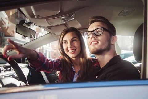 Enjoying travel. Beautiful young couple sitting on the front passenger seats and smiling while