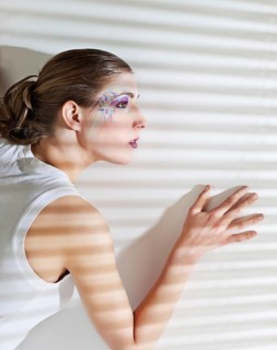 Pretty young woman lean lit by bright sunlight coming through the blinds, Belgium, Europe
