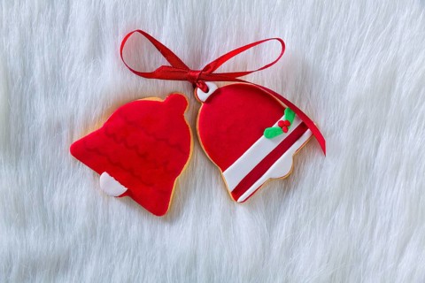 Christmas cookies Xmas red bell shape and ribbon on white fur background