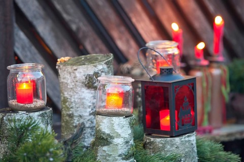 Red candles in glasses and a lantern stand on wood with green branches, borken, münsterland,