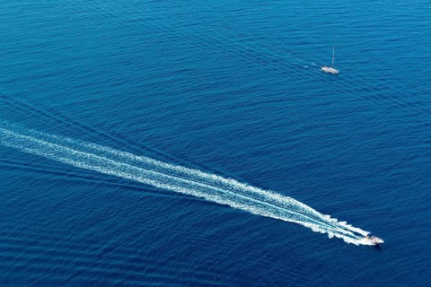 Boat surf foam aerial from prop wash in blue Majorca mediterranean sea
