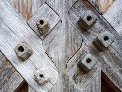 Weathered wooden planks intersecting with decorative square pegs showcasing traditional joinery