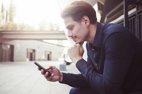 Smiling businessman use a smartphone at street