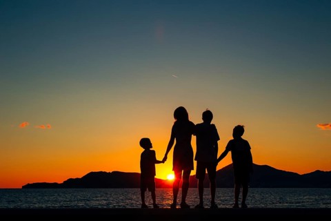 Silhouette of a family with children against the backdrop of the setting sun and sea in Montenegro