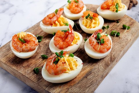 Boiled eggs stuffed with yolk and seasoned with mayonnaise, stuffed eggs with shrimp, on a wooden