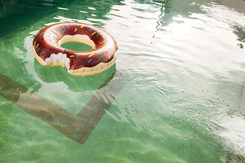 A swimming circle in the form of a bitten doughnut floats in the water of the pool.