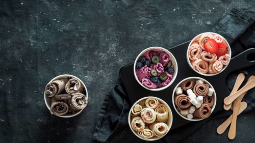 Rolled ice cream in cone cups on dark background. Different iced rolls top view or flat lay. Thai