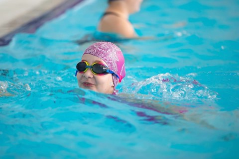 Child athlete swims in the pool. Swimming section