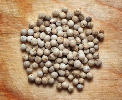 Spices, white pepper peppercorns macro on wooden board