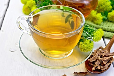 Herbal tea in a glass cup, a teapot on a napkin, spoon with dry roots of Rhodiola rosea, fresh