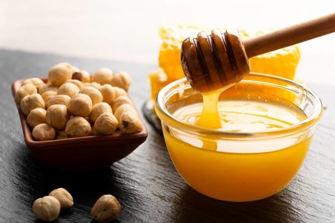 Slate tray with honey hazelnuts and honeycomb on kitchen table, food photography, food photography
