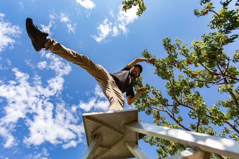 Low angle view of a caucasian man on the top of a ladder standing on one leg. as he enjoying