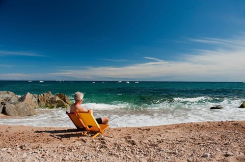Elderly man at orange and yellow chairs on the tranquil beach