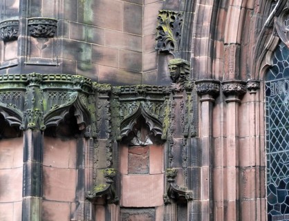 Details of ornately carved medieval stonework with niches and faces on the facade of chester