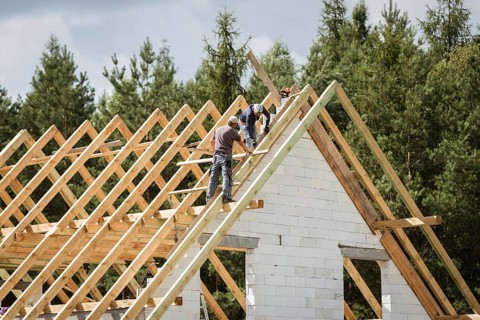 Two men work on the roof of house construction