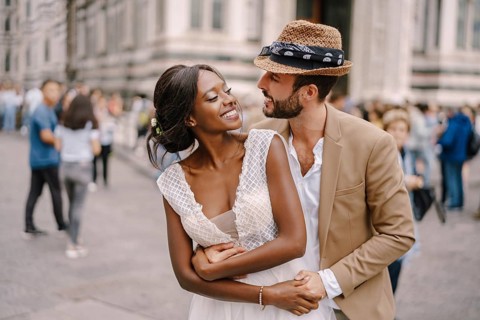 Wedding in Florence, Italy. Caucasian groom hugs from behind African-American bride at Piazza del