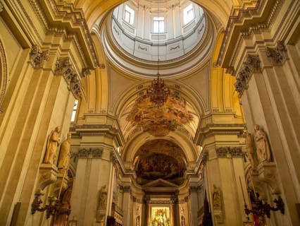 Impressive interior view of a baroque church with high columns and ornate frescoes on the ceiling,