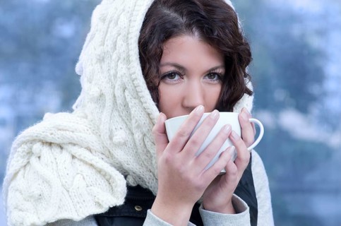 Pretty young caucasian brunette woman wearing white scarf with hood in a outdoor winter portrait