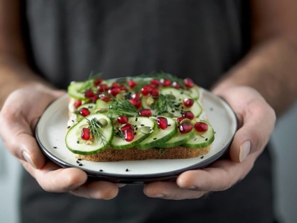 Hands takes plate with vegan sandwich. Healthy appetiezer - whole wheat bread toast with cucumber,