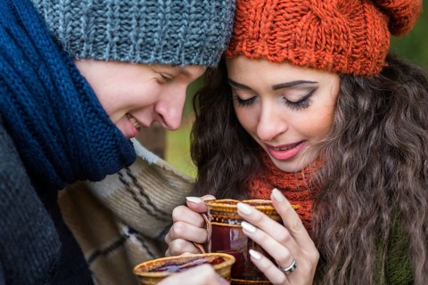 Young couple in love with a cup of coffee in the autumn garden