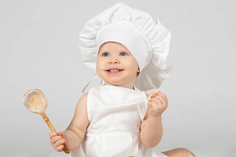 Child cooking. Beautiful little girl in cooking clothes with a big spoon. The child is one year old