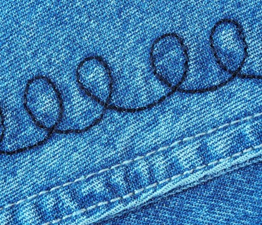 A detailed view of a piece of denim jeans fabric with a spiral pattern