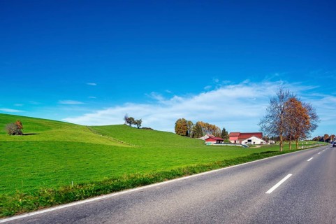Autumn country road, meadows, trees and farm, blue sky near Leutkirch, Allgäu, Bavaria, Germany,