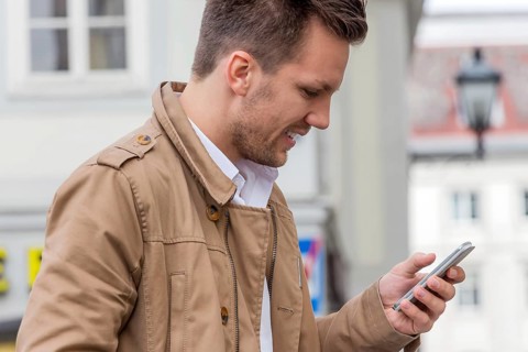 A man writes a text message on his mobile phone. Communication with a smart phone Austria