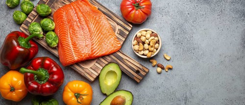 Fresh raw salmon fillet on wooden cutting board, organic bio vegetables and nuts on rustic stone