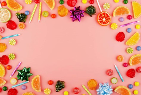 Flat lay view at sweetframe of different type color and taste candies and birthday candles on pink.