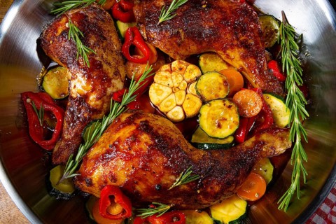 Roasted chicken legs with various vegetables and spices
