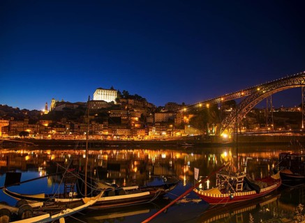 Old town river area of porto in portugal at night with rabelo boats