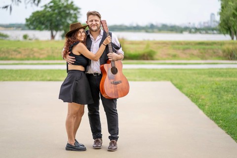 Couple of musicians pose looking at the camera in a park