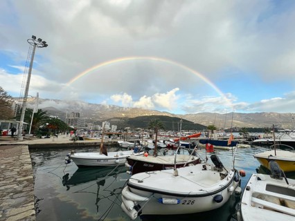 Yachts moored at the pier against the backdrop of a rainbow over the mountains.
