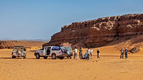Off-road vehicle and people in a sunny desert landscape with impressive rock formations, Off-road