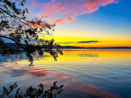 Colourful sunset on Lake Sempach with pink and blue sky reflections in the water, Sempach, Lucerne,