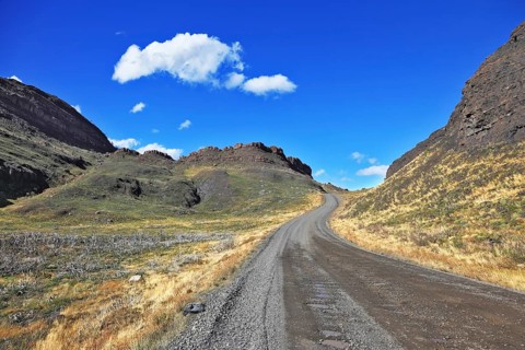 Beautifully curved gravel road between the hills. The National Park Torres del Paine. Chilean