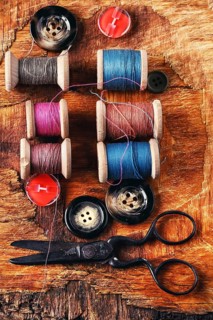 Six antiquated sewing threads and buttons on retro background