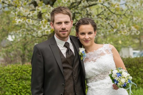 Bride and groom stand in the park in front of a blossoming fruit tree, Austria, Europe