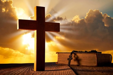 Christian wood cross on sunset sky wooden made with Bible and rosary beads